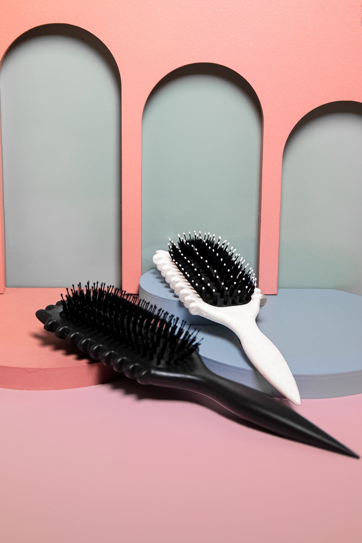 Estetisk bild av beige lockdefinierande borste med färgglad bakgrund i grön, blå och rosa – perfekt för naturliga lockar