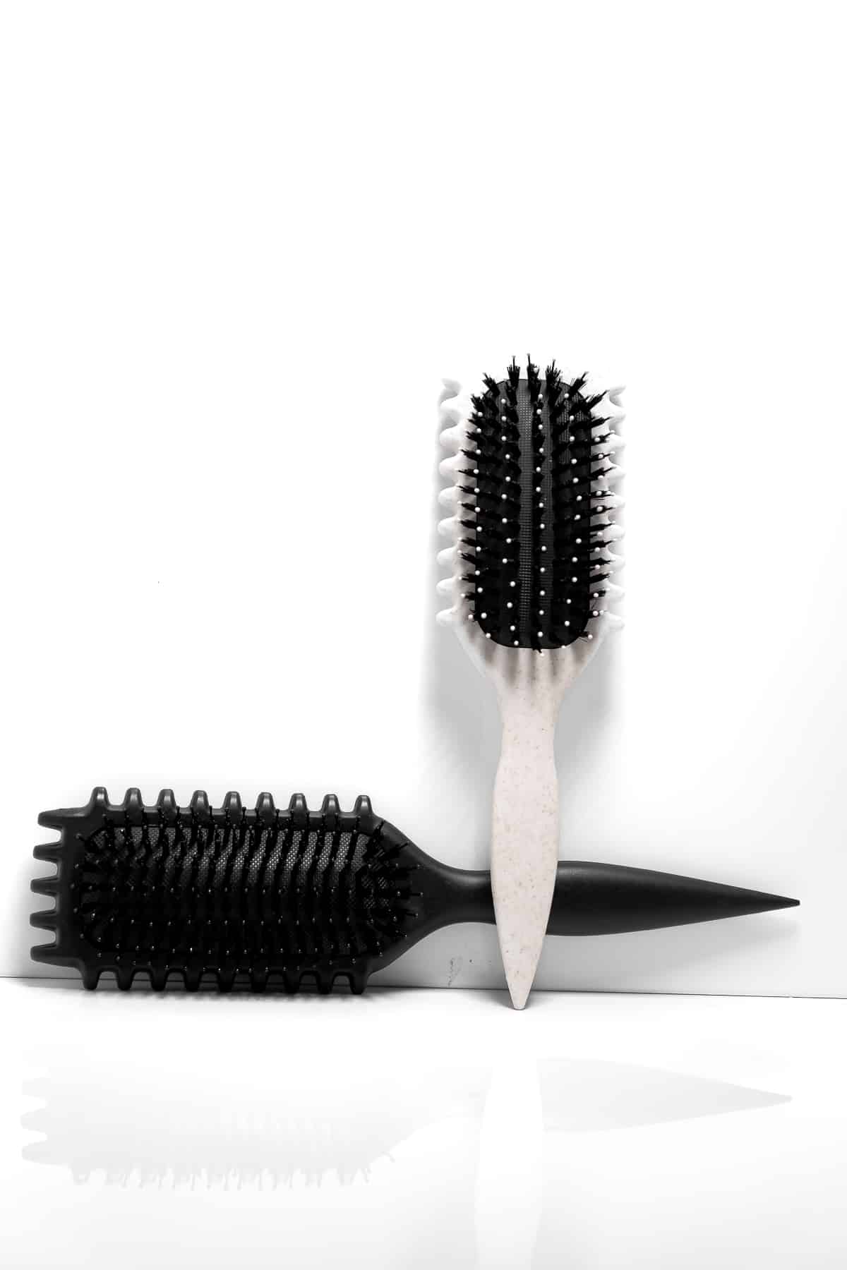 Estetisk bild av Bounce Curl Define Brush – svart liggande och beige stående borste för naturliga lockar