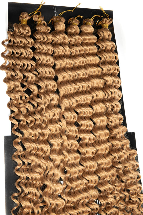 Goddess Boho Braids i ljus honungsblond färg med glänsande, fjäderlätta lockar. Perfekta för mjuka, naturliga flätor med bohemisk elegans och volym.