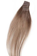 Närbild på äkta hår extensions med tejp, som visar en balayage-effekt med slingor i brunt och blont för en naturlig och volymrik look