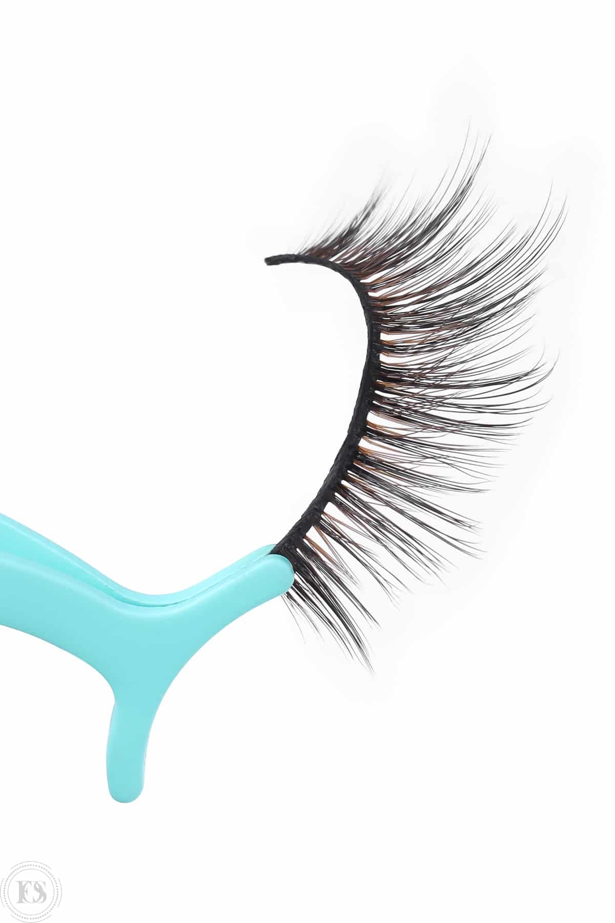 Detaljbild på lösgonfransar hållna med turkos tång, perfekt för att visa produktens kvalitet och applicering