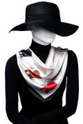 Mannequin klädd i svart hatt och polotröja, med en elegant silkesliknande scarf i vitt, beige, svart och rött mönster draperad runt halsen.