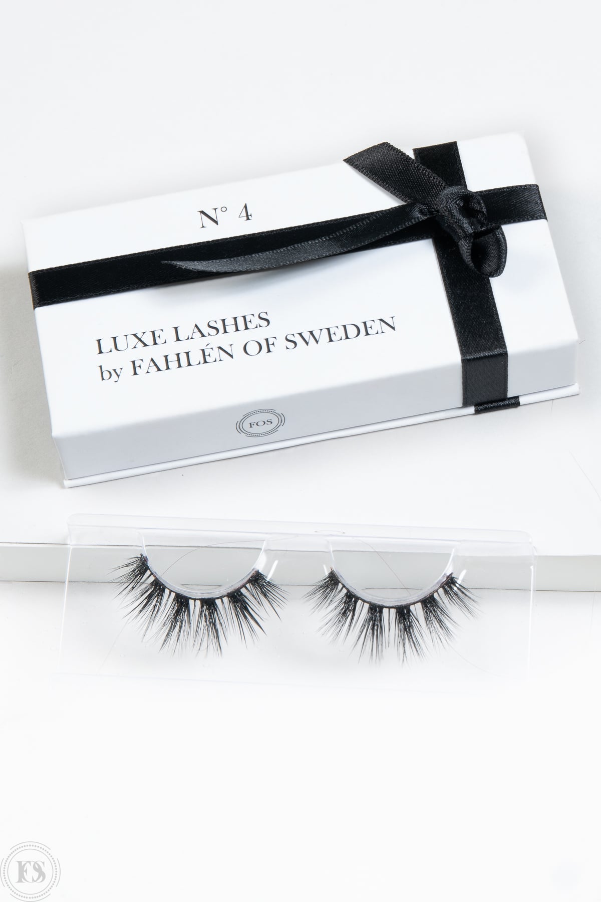 lösögonfransar i en vit ask med svart band och texten Luxe Lashes by Fahlén of Sweden No. 4, placerade framför förpackningen på ett vitt underlag.