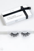 Eleganta lösögonfransar i en vit ask med svart band och texten Luxe Lashes by Fahlén of Sweden No. 10, placerade framför förpackningen på ett vitt underlag.